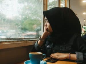 Muslim girl suffering depression, looks out window. Photo by MuhammadRuqiYaddin